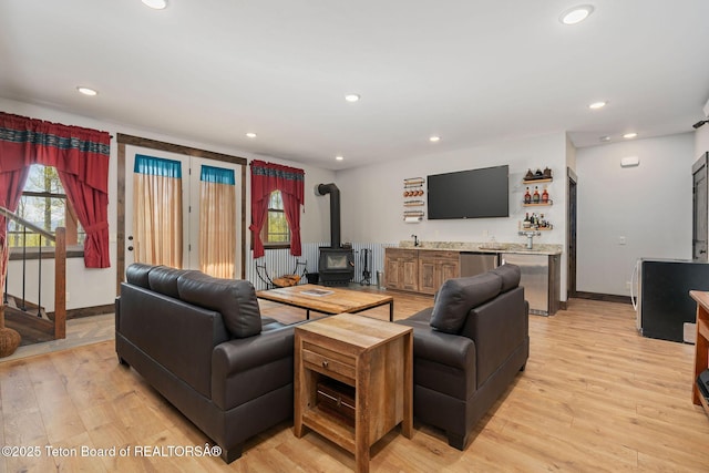 living area with a wood stove, wet bar, recessed lighting, baseboards, and light wood-style floors