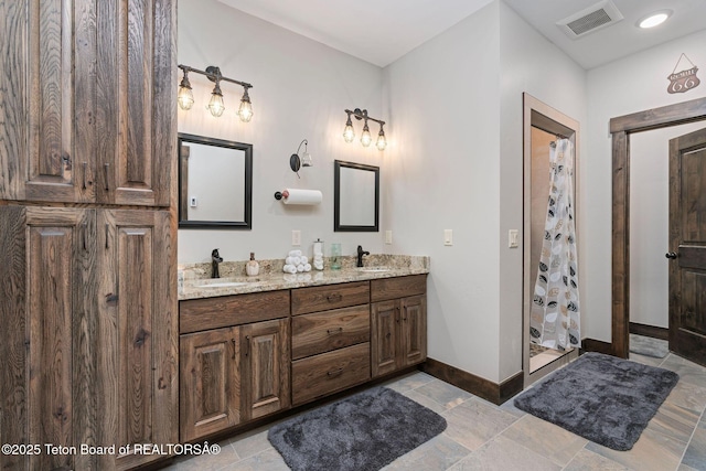 full bath with a sink, visible vents, a shower stall, double vanity, and baseboards