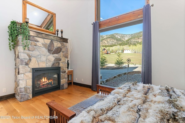 bedroom featuring baseboards, a fireplace, a mountain view, and wood finished floors