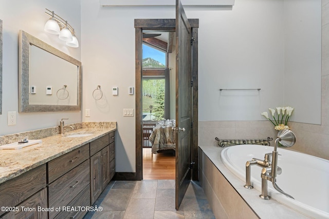 bathroom featuring a bath, connected bathroom, baseboards, and vanity