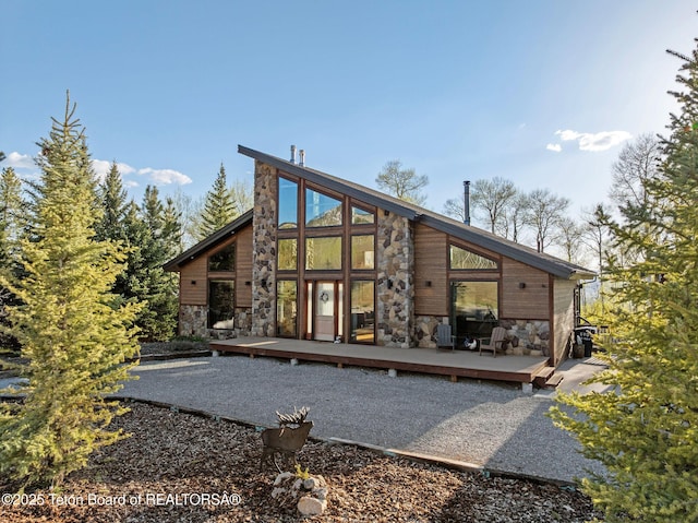 back of property with stone siding and a wooden deck