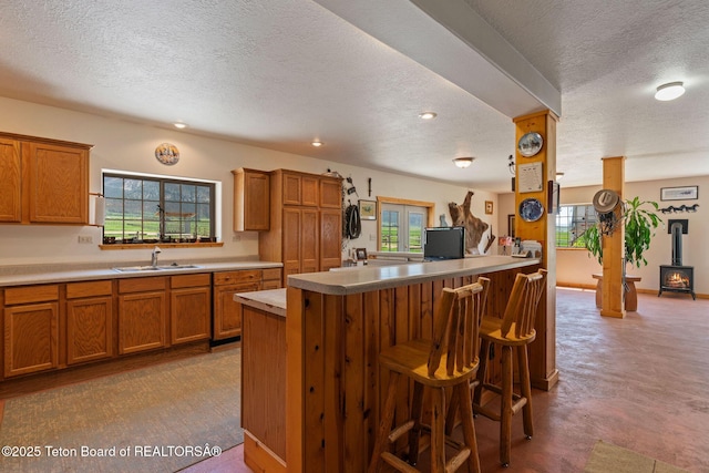 86 Hawks Rest Rd, Etna, WY 83118 - kitchen featuring a textured ceiling, a sink, brown cabinetry, a wood stove, and recessed lighting