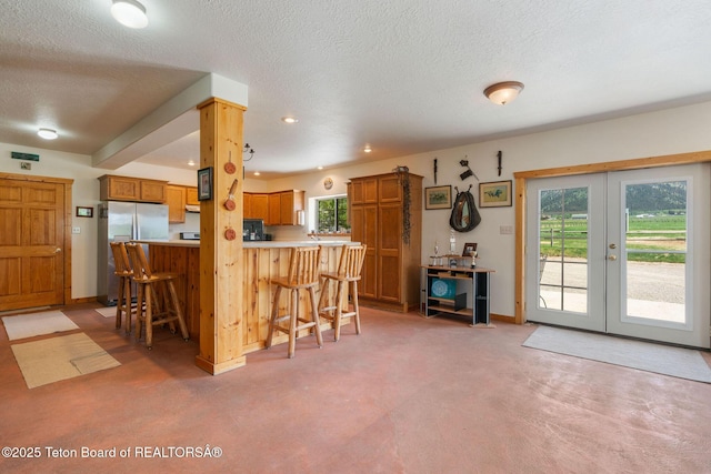 86 Hawks Rest Rd, Etna, WY 83118 - kitchen with a kitchen breakfast bar, brown cabinets, light countertops, freestanding refrigerator, and a peninsula