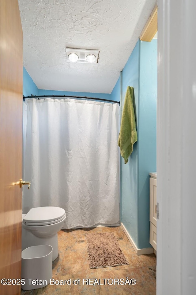 611 W Ramshorn St, Dubois, WY 82513 - bathroom featuring toilet, a textured ceiling, baseboards, and a shower with curtain