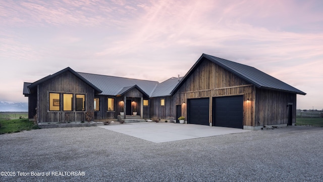 view of front of house with a garage, board and batten siding, driveway, and metal roof