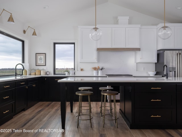 kitchen with light countertops, dark cabinets, plenty of natural light, and lofted ceiling