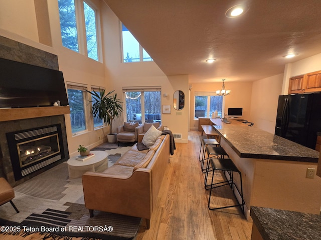 living room featuring a notable chandelier, recessed lighting, baseboards, light wood finished floors, and a tile fireplace