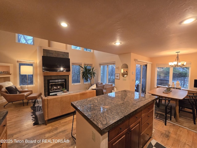 kitchen featuring a glass covered fireplace, light wood-style floors, a chandelier, and recessed lighting