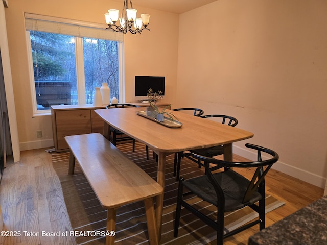 dining room with wood finished floors, a chandelier, and baseboards