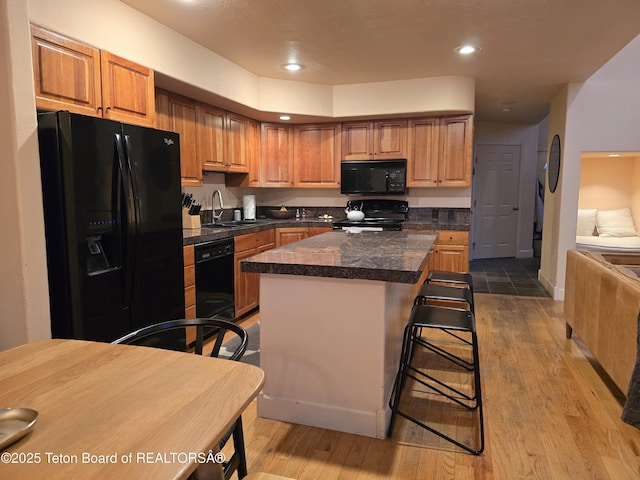 kitchen with a sink, tile countertops, black appliances, and wood finished floors