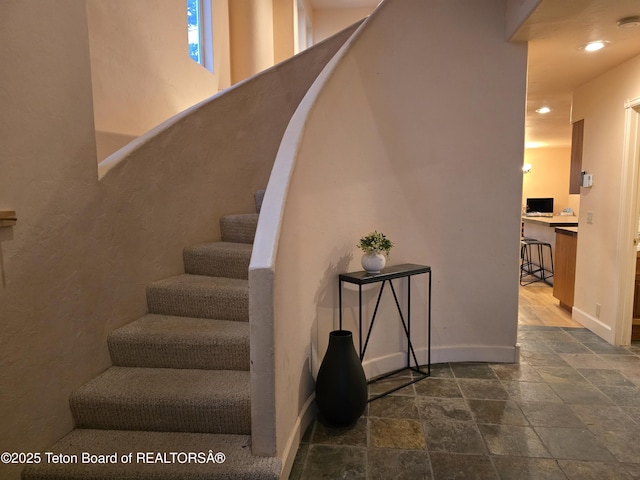 stairway with recessed lighting, baseboards, and stone tile flooring