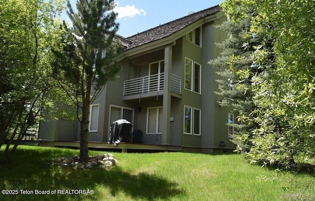 back of property with a balcony and a lawn