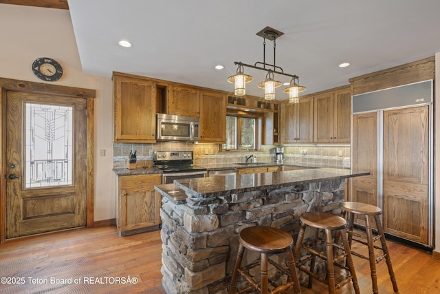 7250 N Rachel Way Unit 6, Teton Village, WY 83025 - kitchen with appliances with stainless steel finishes, a sink, tasteful backsplash, a kitchen island, and dark stone countertops