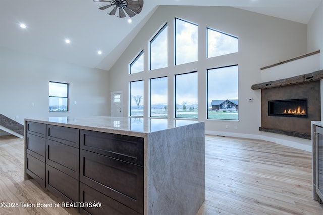4444 Tails Down Rd, Tetonia, ID 83452 - kitchen featuring open floor plan, high vaulted ceiling, a warm lit fireplace, light stone counters, and light wood-style floors