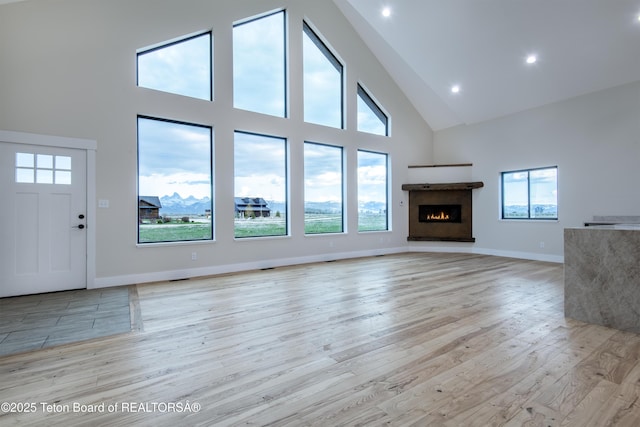 4444 Tails Down Rd, Tetonia, ID 83452 - unfurnished living room featuring high vaulted ceiling, healthy amount of natural light, light wood-style flooring, a warm lit fireplace, and recessed lighting