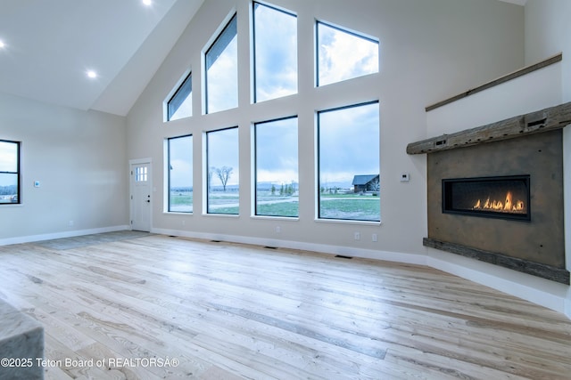 4444 Tails Down Rd, Tetonia, ID 83452 - unfurnished living room featuring high vaulted ceiling, a glass covered fireplace, wood finished floors, and baseboards
