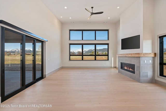 1404 Canyon Sunrise, Driggs, ID 83422 - unfurnished living room featuring a towering ceiling, a tiled fireplace, wood finished floors, plenty of natural light, and recessed lighting