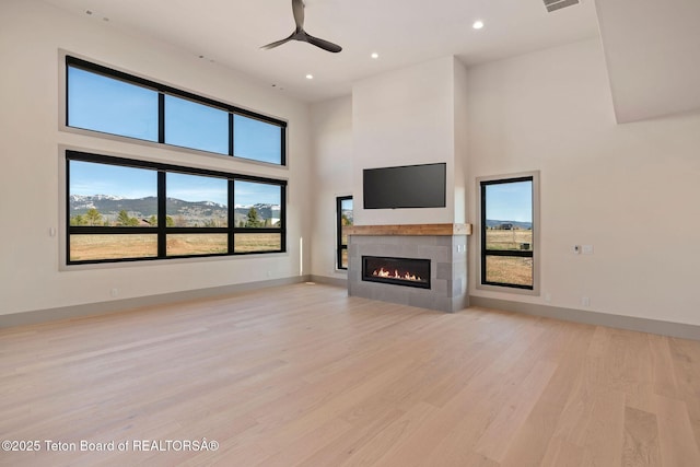 1404 Canyon Sunrise, Driggs, ID 83422 - unfurnished living room featuring a towering ceiling, a tiled fireplace, light wood-type flooring, ceiling fan, and recessed lighting