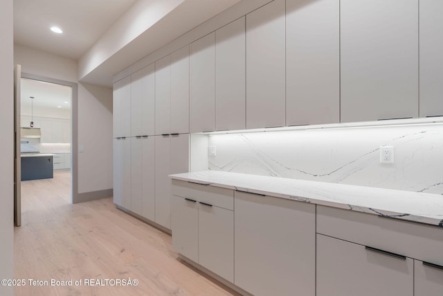 1404 Canyon Sunrise, Driggs, ID 83422 - kitchen with light wood-style flooring, light stone countertops, modern cabinets, recessed lighting, and white cabinetry