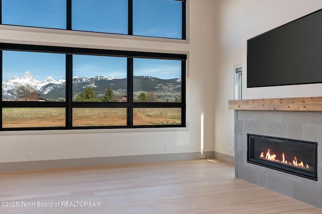 1404 Canyon Sunrise, Driggs, ID 83422 - unfurnished living room with a tiled fireplace, wood finished floors, baseboards, and a towering ceiling