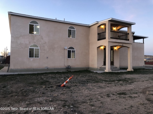 rear view of house with stucco siding and a balcony