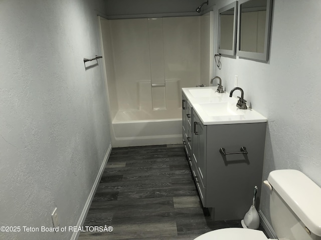 full bath featuring shower / bath combination, toilet, vanity, wood finished floors, and a textured wall