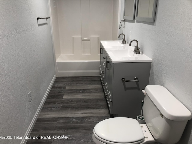 full bathroom featuring vanity, a textured wall, baseboards, and wood finished floors