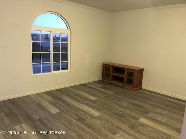 empty room with baseboards, crown molding, and wood finished floors