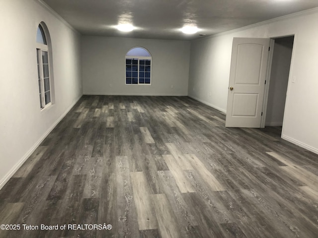 unfurnished room with baseboards, crown molding, and dark wood-style floors