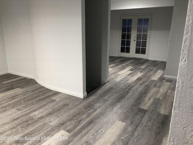 empty room with baseboards, french doors, and wood finished floors