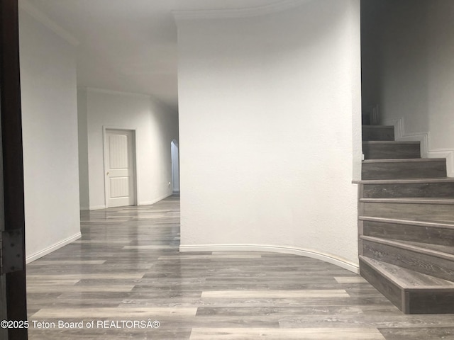 stairs with crown molding, baseboards, and wood finished floors