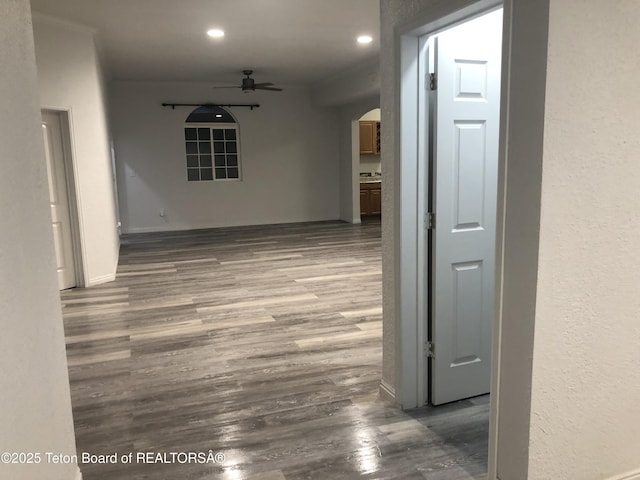 hall with arched walkways, baseboards, recessed lighting, and wood finished floors