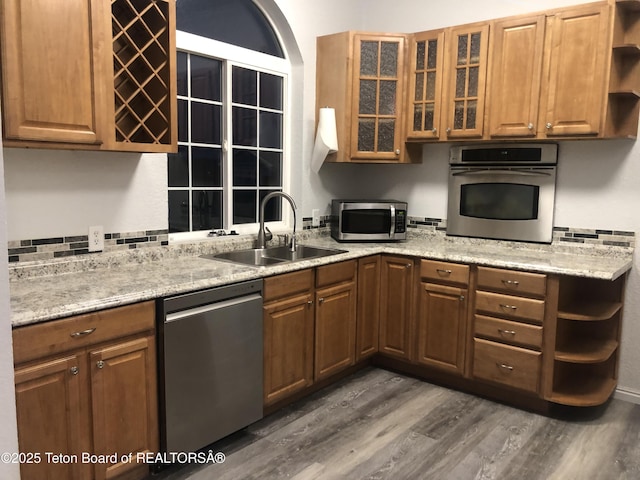 kitchen with a sink, open shelves, dark wood-style floors, glass insert cabinets, and appliances with stainless steel finishes