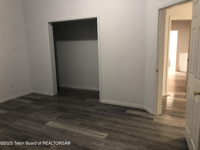 unfurnished bedroom with baseboards, a closet, and dark wood-style floors
