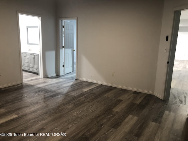 spare room featuring baseboards and dark wood-type flooring