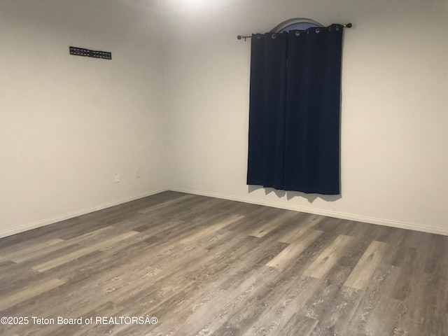 spare room with baseboards and dark wood-style floors