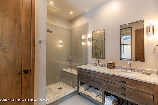 bathroom featuring double vanity, tile patterned flooring, a shower stall, and a sink