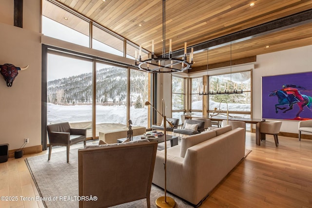 living area with a mountain view, baseboards, wood-type flooring, wood ceiling, and a chandelier