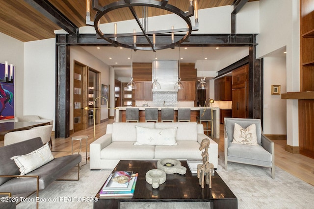 living room with baseboards, beamed ceiling, and light wood finished floors
