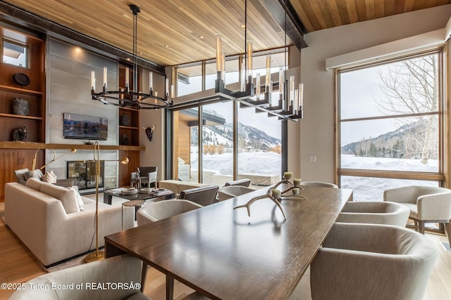 dining space with a wealth of natural light, an inviting chandelier, wooden ceiling, and wood finished floors