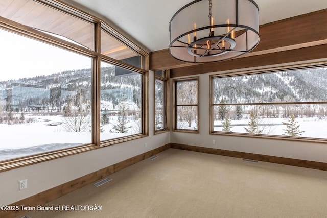 unfurnished sunroom featuring a mountain view, visible vents, a healthy amount of sunlight, and a notable chandelier