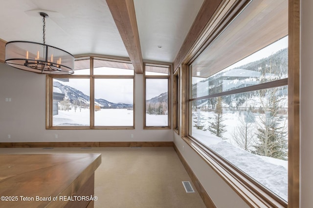 unfurnished dining area featuring a mountain view, an inviting chandelier, visible vents, and beamed ceiling