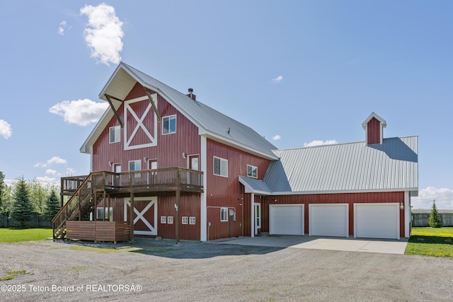 view of front of house featuring stairs, driveway, metal roof, and a barn