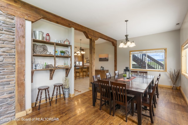 dining space featuring an inviting chandelier, visible vents, wood finished floors, and baseboards