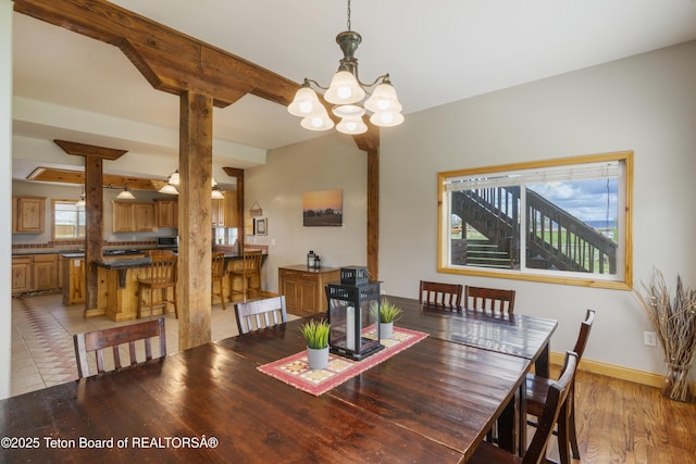 dining space with light wood-type flooring, a notable chandelier, beam ceiling, and baseboards