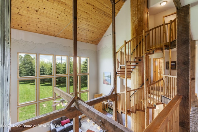 stairway with wood ceiling, a healthy amount of sunlight, and high vaulted ceiling