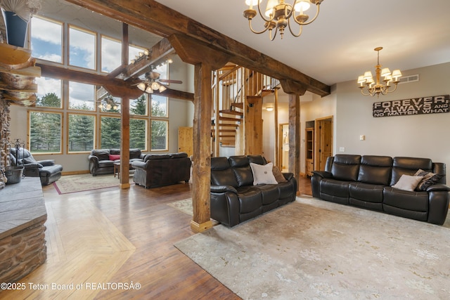 living area featuring stairs, ceiling fan with notable chandelier, visible vents, beamed ceiling, and baseboards
