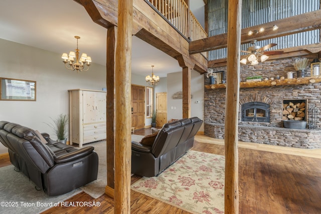 living area featuring a fireplace, ceiling fan with notable chandelier, a high ceiling, and wood finished floors