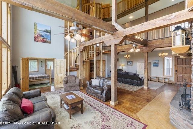 living room with a wealth of natural light, stairway, a towering ceiling, and ceiling fan with notable chandelier