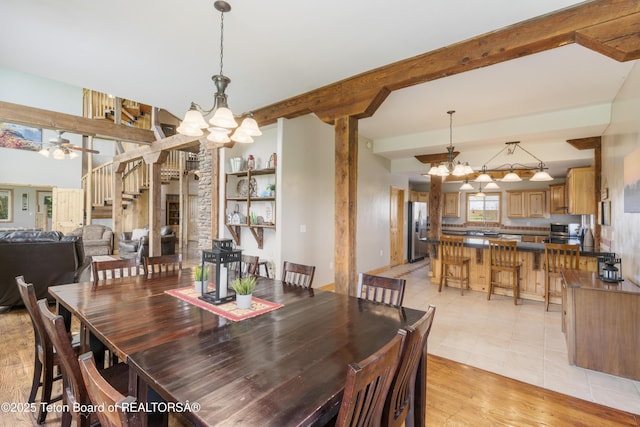dining space with stairs, beamed ceiling, light tile patterned flooring, and ceiling fan with notable chandelier